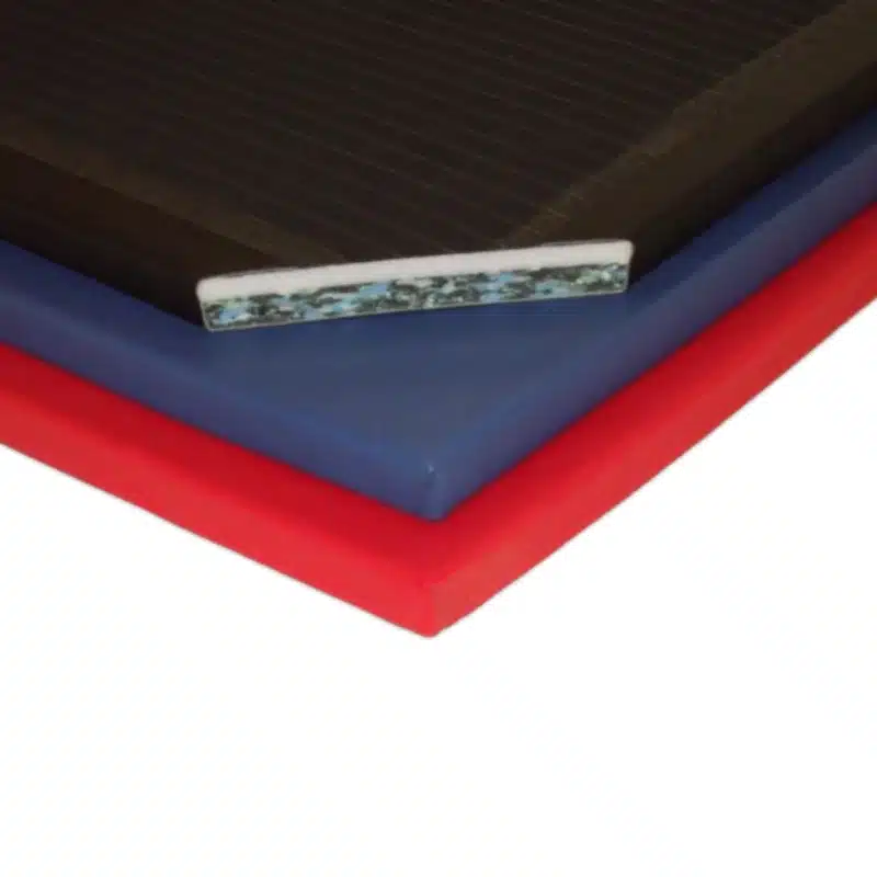 Cross-section of a blended gym mat showing dual-foam layers with soft chip foam on top and firmer closed-cell polyethylene beneath, all wrapped in coloured PVC.