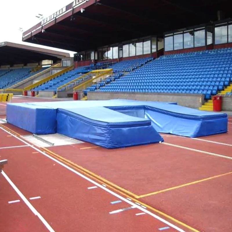 GMLM070 Blue pole vault landing mat system set up on athletics track with stadium seating behind.